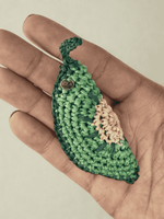 Load image into Gallery viewer, Kiwi Slice raffia charm held in hand, subtle green tones