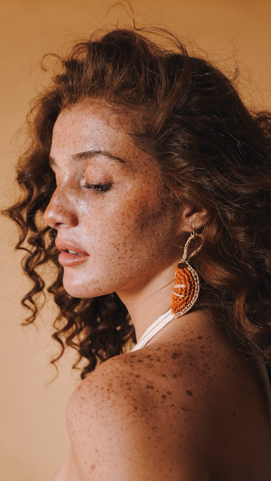 Boucle orange en raffia portée par une modèle