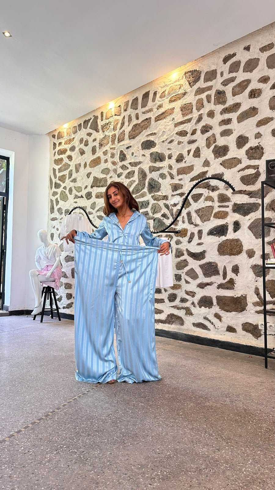 Démonstration de la largeur ajustable d’un pantalon Jawhara bleu à l’atelier