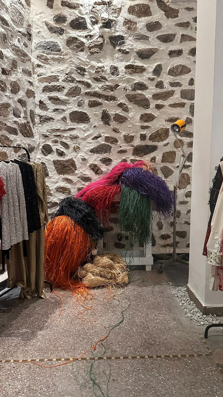 Écheveaux de raffia colorés devant le mur de pierre de l’atelier YZA