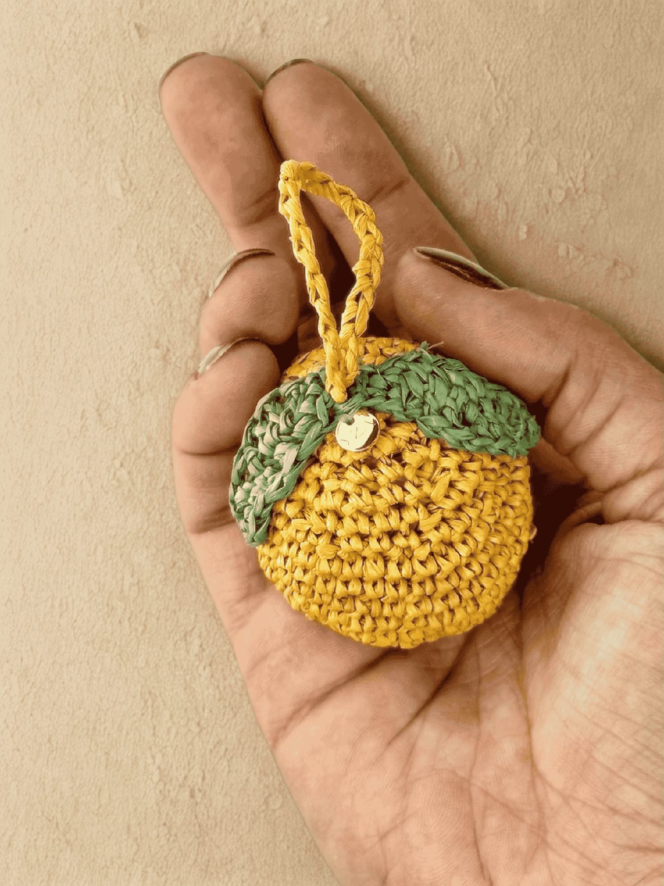 Charm citron en raffia tenu dans la main