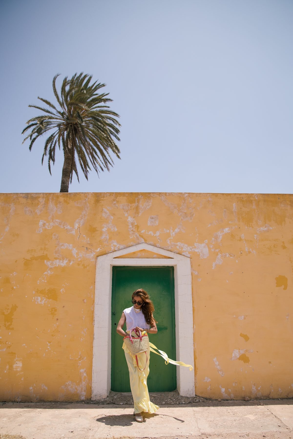 Look estival YZA en raphia devant un mur ocre