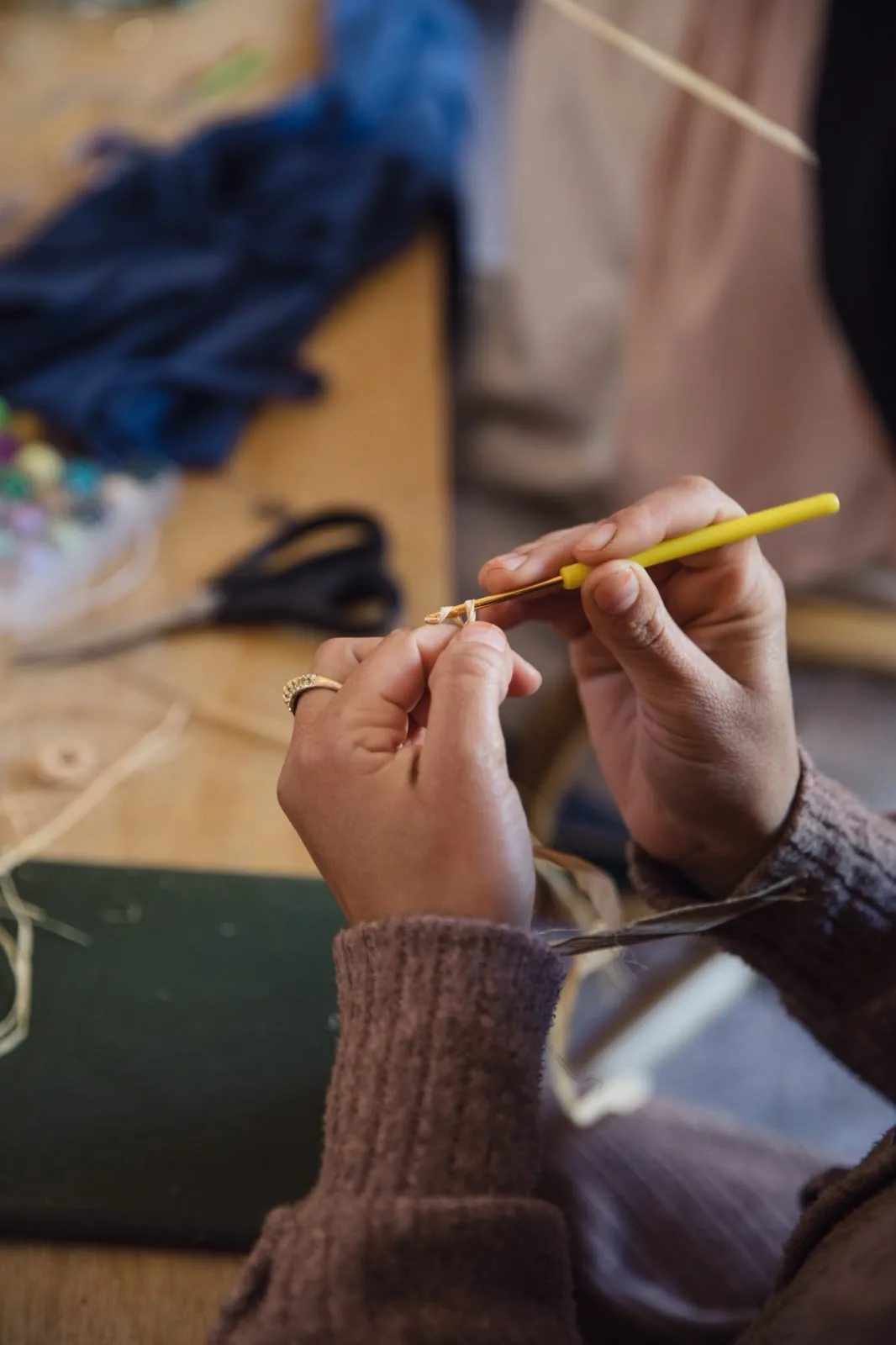 Les mains d’une artisane YZA au crochet, un brin de raphia entre les doigts