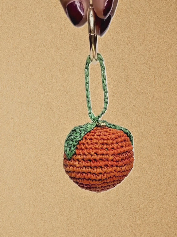 Whole Orange charm clipped to straw basket; slow pan highlighting shape and colour