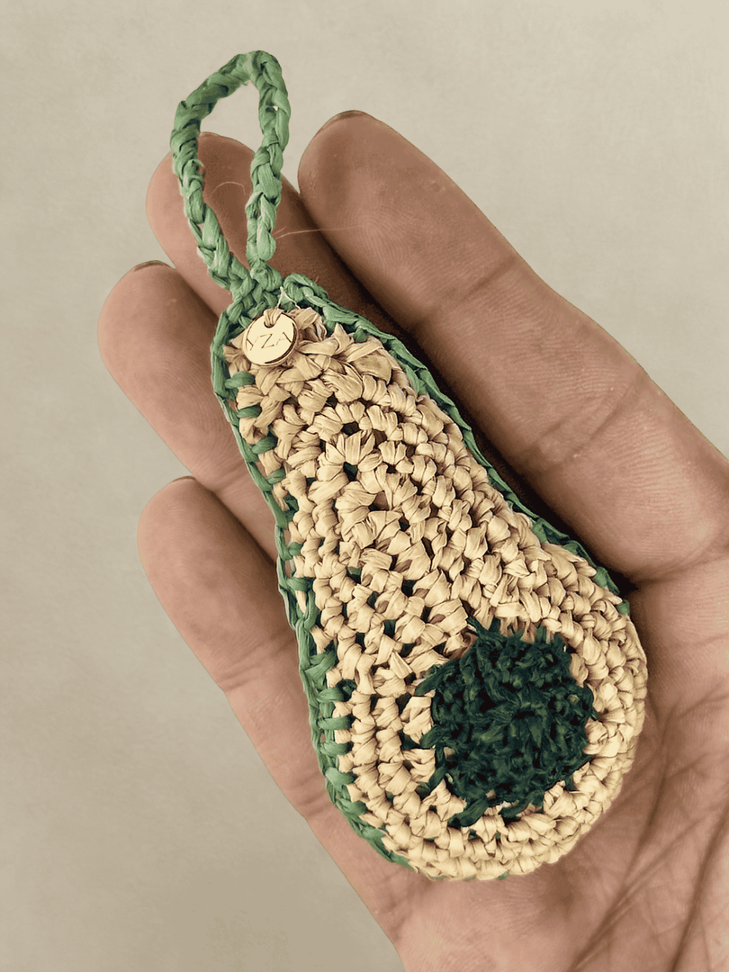 Avocado raffia charm in hand, green tones and pit detail