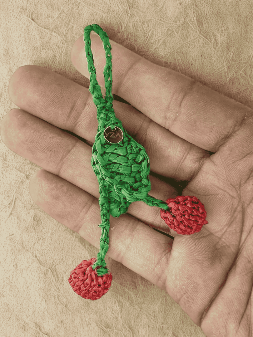 Cherries raffia charm held in hand, twin fruits visible
