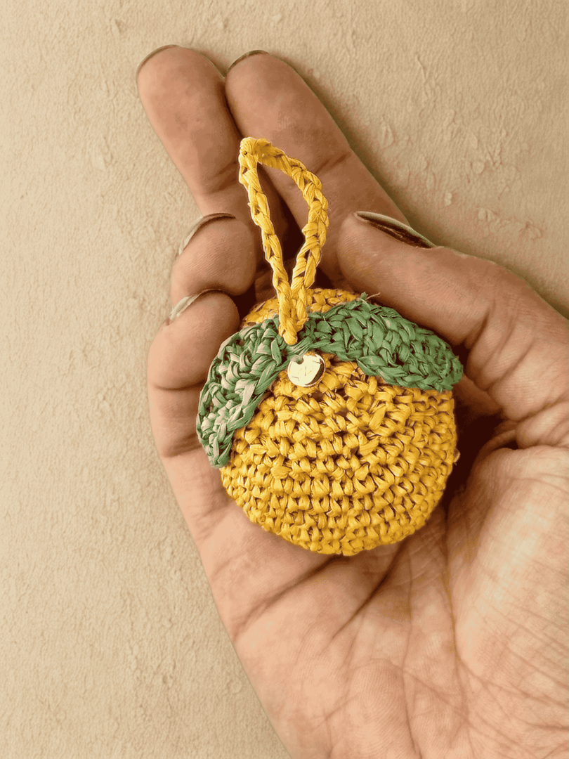 Lemon raffia charm held in hand, bright yellow