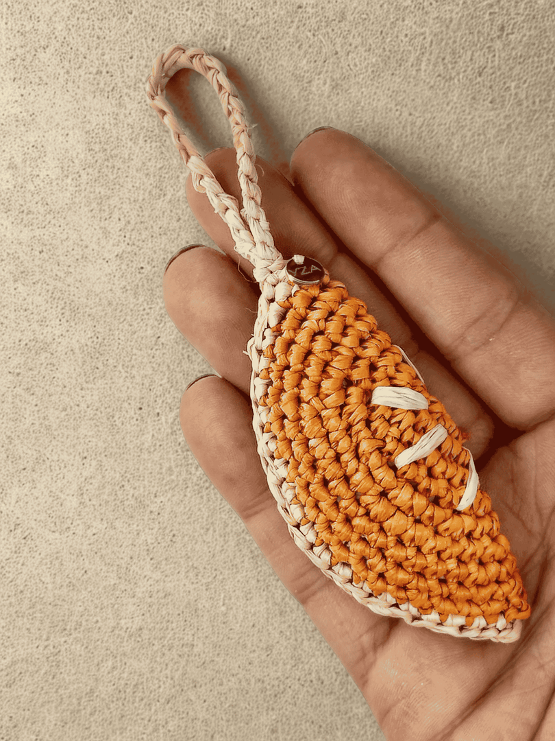Orange Slice raffia charm in hand, stitch detail visible