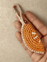 Load image into Gallery viewer, Orange Slice raffia charm in hand, stitch detail visible
